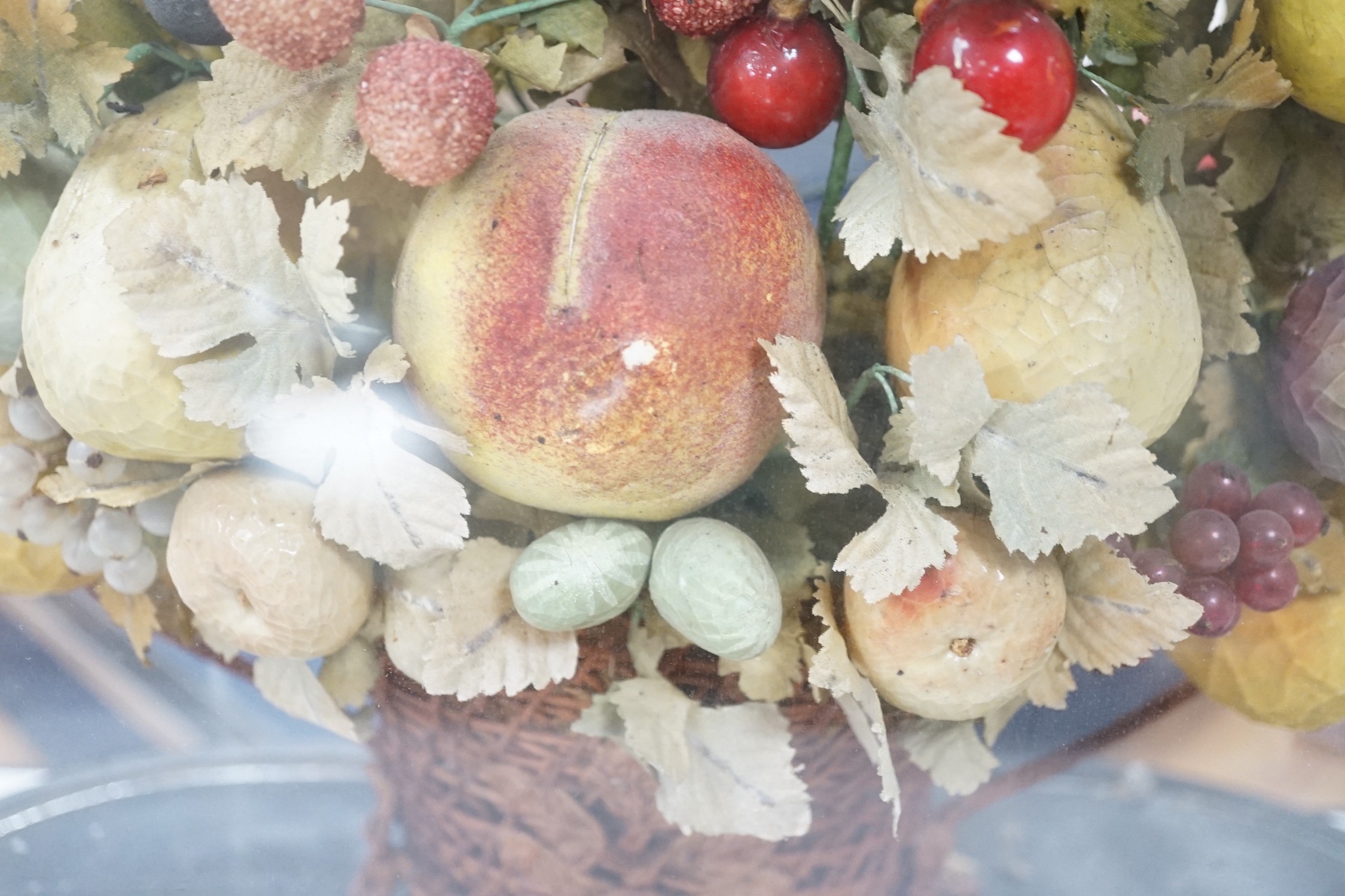 A Victorian display of papier mache fruit in a basket, under a glass dome, 55cms high